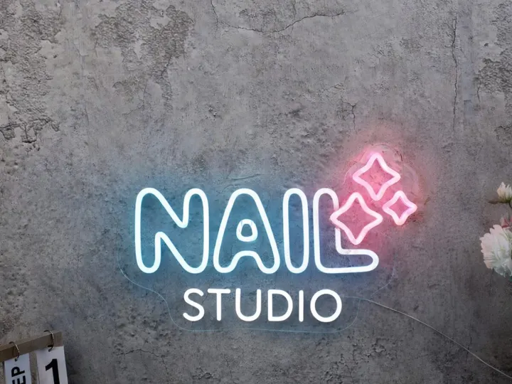 Weiß-pinkes Nail-Studio LED-Neonschild an einer hellen Betonwand